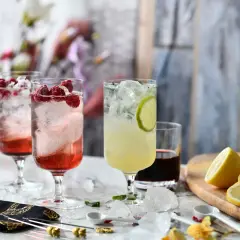 Trzy orzeźwiające drinki z malinami i limonką, na stole z cytrynami i lodem.