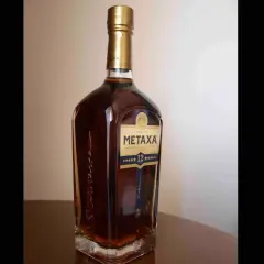 Butelka greckiego brandy Metaxa 12 gwiazdek na stole.