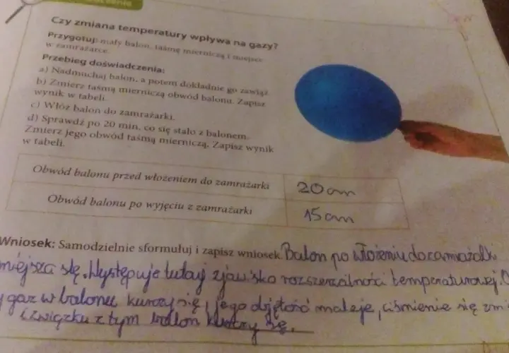 Niebieski balon i fragment ręki trzymającej taśmę mierniczą na tle tekstu o doświadczeniu.