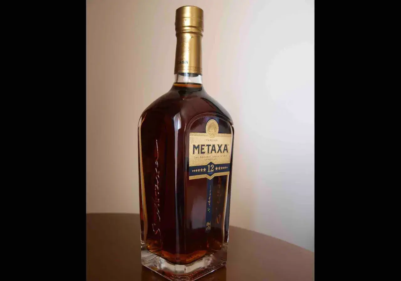 Butelka greckiego brandy Metaxa 12 gwiazdek na stole.